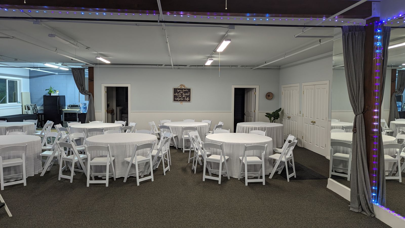 Indoor event space with round tables and festive lighting set for a celebration